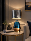 Blue Glass and Gold Base Luxury Table Lamp with smoked drum shade on marble side table