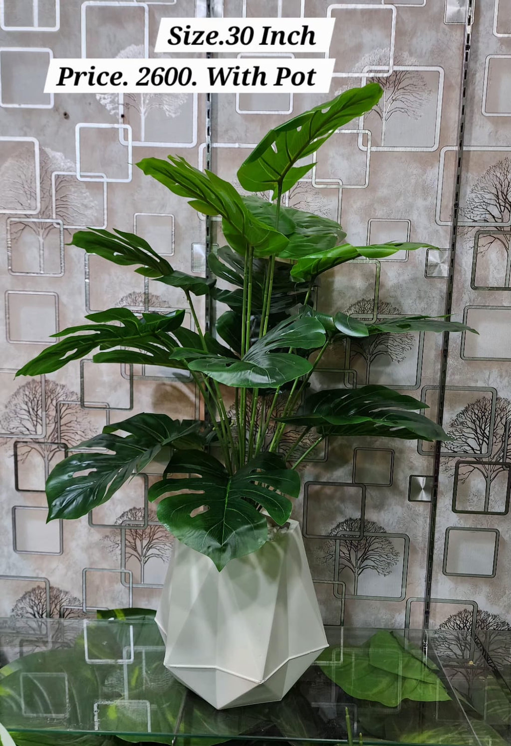 Artificial tropical plant with yellow-green leaves in white geometric pot