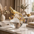 Crystal brass parrot figurine with amethyst flowers and crystal glass sphere base on marble surface