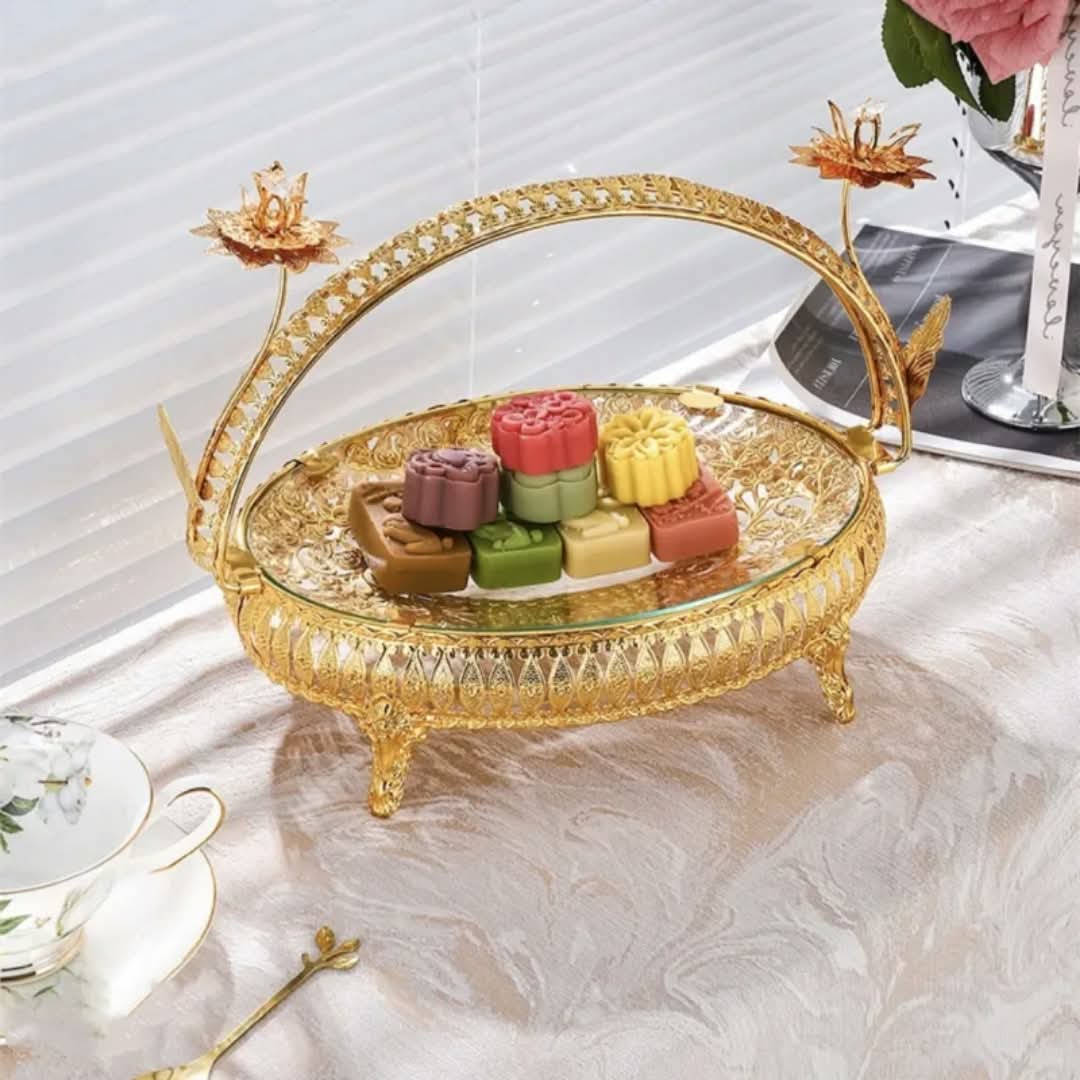 Ornate gold serving tray with arch handle on a marble table