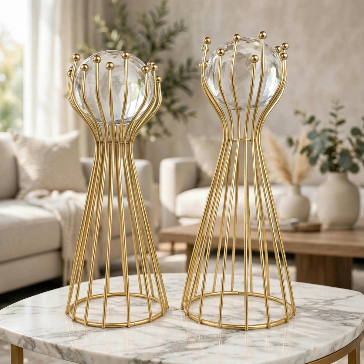 Pair of crystal ball gold wire stand sculptures displayed on a marble coffee table in a luxury living room