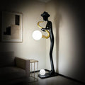 Black saxophone player floor lamp with gold saxophone and glowing white orb